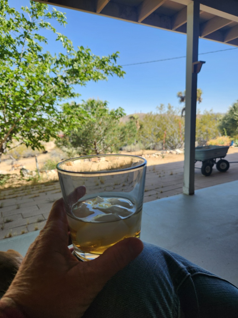 glass of whiskey in hand on desert porch